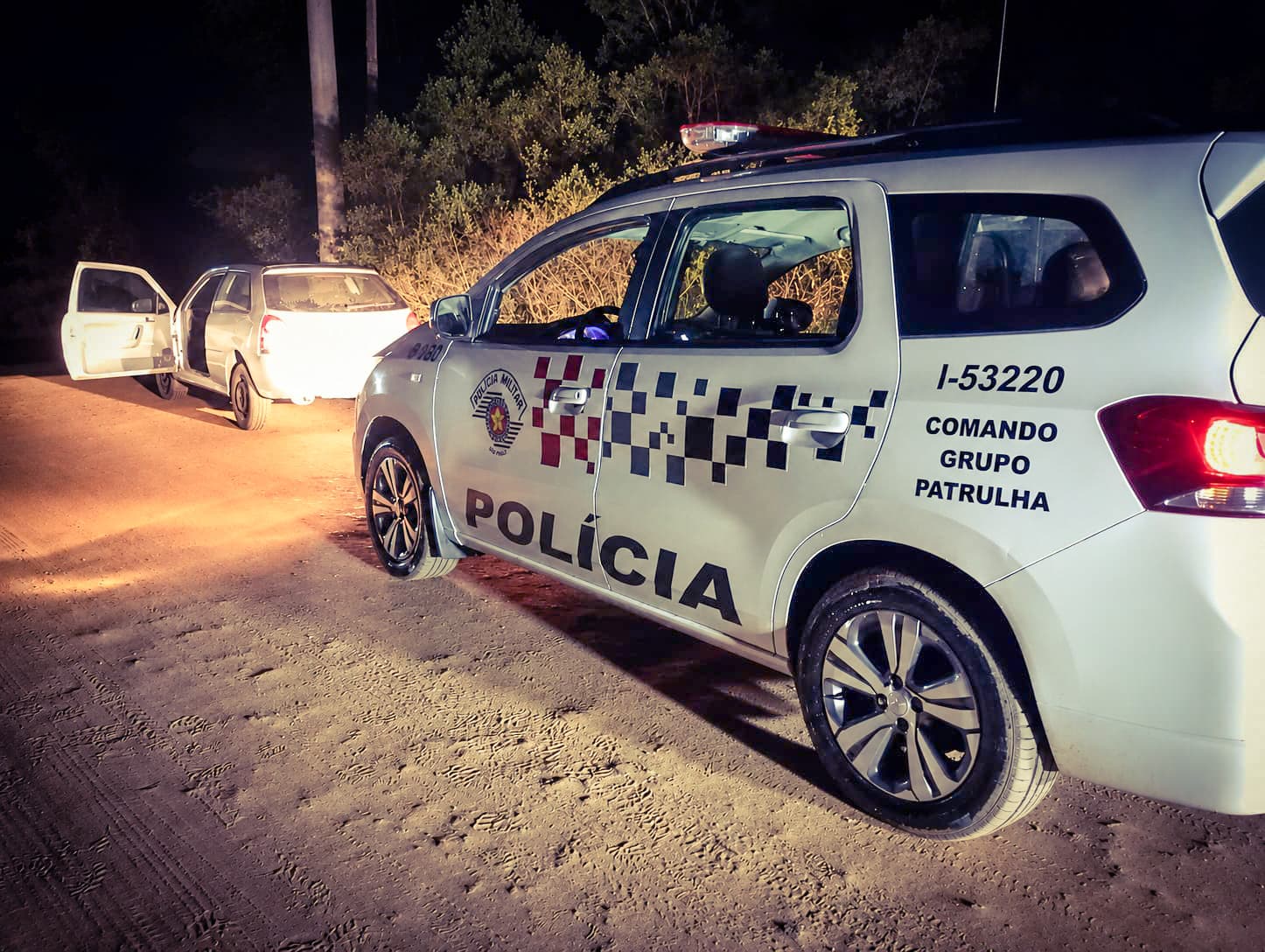 Fotografia de uma ação da Polícia Militar. Policiais aparecem ao lado de um veículo recuperado durante uma ocorrência, em uma área urbana. A imagem ilustra o trabalho das equipes no combate ao tráfico de drogas, na recuperação de bens furtados e na garantia da segurança da população.